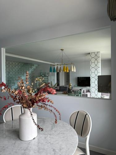 a dining room with a table with a vase of flowers at DÚPLEX DE LUJO EN FOZ CON VISTAS al MAR in Foz