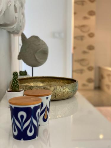 two cups on a table with a bowl and a cactus at DÚPLEX DE LUJO EN FOZ CON VISTAS al MAR in Foz