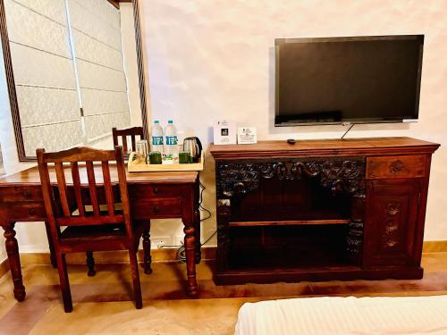 a room with a desk and a television and a table with a chair at The Kaptain's Retreat in Chandīgarh