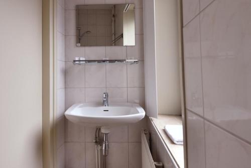 a white bathroom with a sink and a mirror at Royal in Deventer