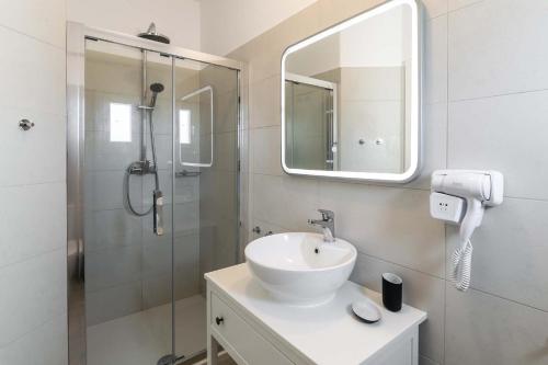 a bathroom with a sink and a shower with a mirror at Sunset Village 6 in Paleochori