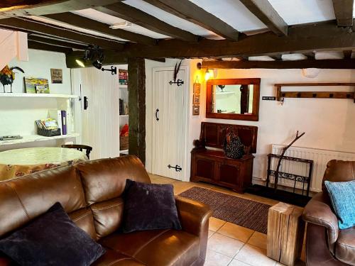 a living room with a leather couch and a mirror at The Roost - Askrigg 18th Century Cottage in Askrigg