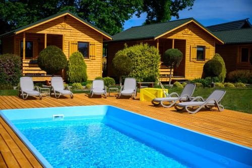 a pool on a deck with chairs and a house at Zielona Trawa in Bobolin