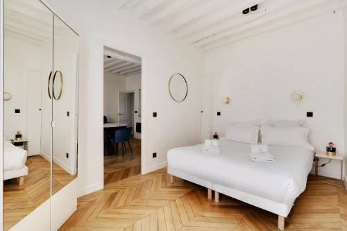 Pick A Flat's Apartment in Jardin du Luxembourg - Rue Royer Collard في باريس: غرفة نوم بيضاء مع سرير أبيض ومرآة