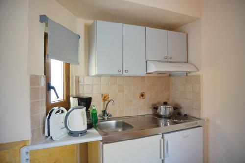 a small kitchen with white cabinets and a sink at Katerini Apartments Hotel in Platanes