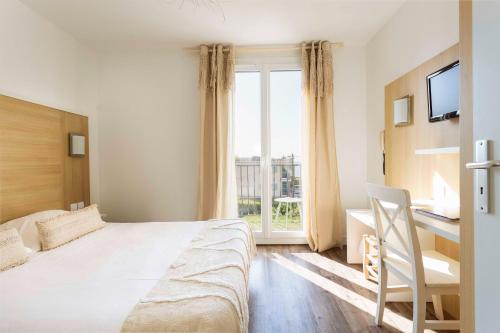 a bedroom with a bed and a desk and a window at Le Relais d'Agay in Agay - Saint Raphael