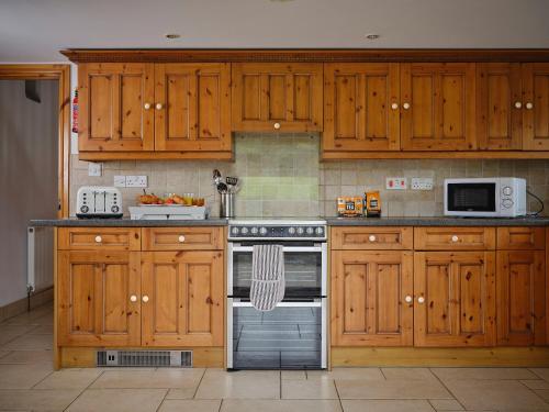 a kitchen with wooden cabinets and a stove top oven at The Granary in Bideford