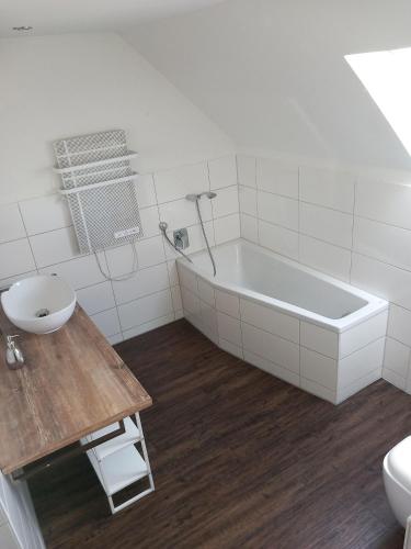 a white bathroom with a tub and a sink at Ferienwohnung am Waldrand in Bechhofen