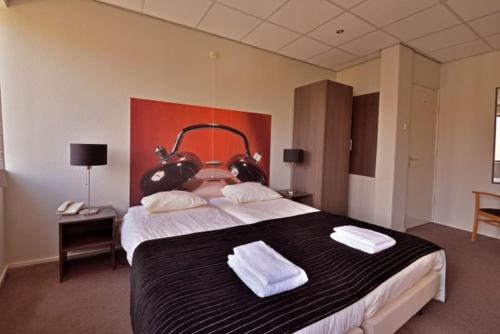 a bedroom with a large bed with two towels on it at Royal in Deventer