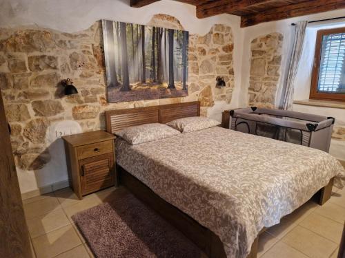 a bedroom with a bed and a stone wall at Apartments P&B in Vabriga