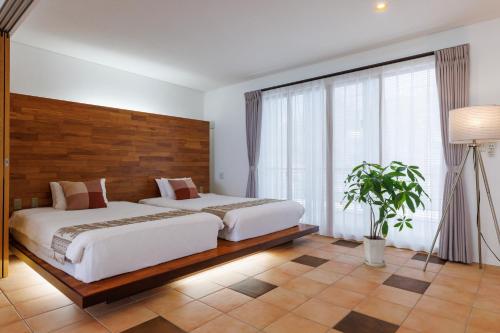 a bedroom with two beds and a large window at 海まで徒歩1分 沖縄でも珍しい絶景ホテル 贅沢プライベートビーチ付き ビーチルーム in Onna