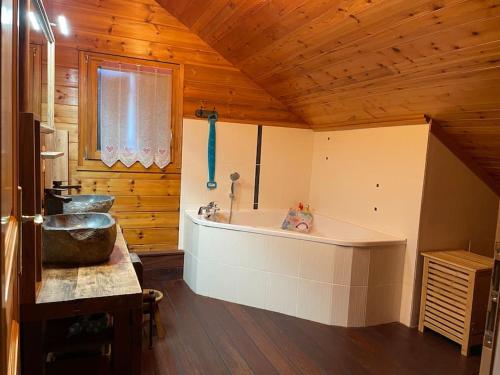 ein Badezimmer mit einer großen Badewanne und einem Waschbecken in der Unterkunft Le chalet blanc de Gerardmer avec Spa in Gérardmer