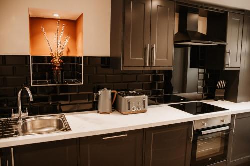 a kitchen with black cabinets and a sink at The Old Brewery, Ulverston in Ulverston