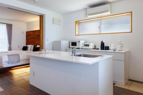 a kitchen with a sink and a living room at 海まで徒歩1分 沖縄でも珍しい絶景ホテル 贅沢プライベートビーチ付き ビーチルーム in Onna