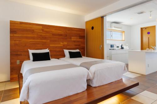 two beds in a hotel room with a kitchen at 海まで徒歩1分 沖縄でも珍しい絶景ホテル 贅沢プライベートビーチ付き ビーチルーム in Onna