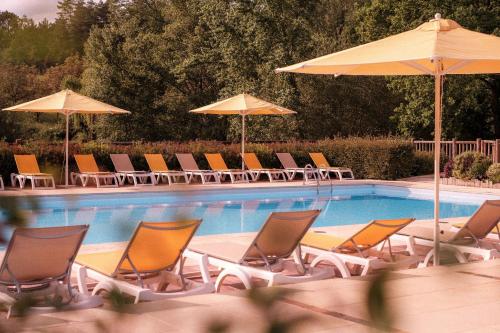 a group of chairs and umbrellas next to a swimming pool at Slow Village Séveilles - Périgord in Valades