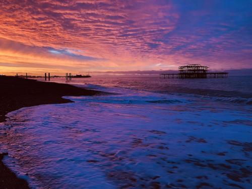 einen Sonnenuntergang über einem Strand mit einem Pier im Wasser in der Unterkunft Central Brighton flat, 3 bedrooms, sleeps 6, close to shops and beach in Brighton & Hove