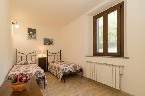 a bedroom with two beds and a table and a window at Villa Adelmo in Pomarance
