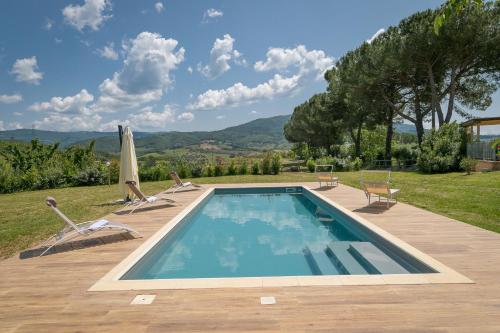 a swimming pool with two chairs and an umbrella at Villa Adelmo in Pomarance