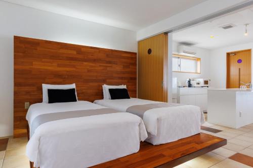 two beds in a hotel room with a kitchen at 海まで徒歩1分 沖縄でも珍しい絶景ホテル 贅沢プライベートビーチ付き ビーチルーム in Onna