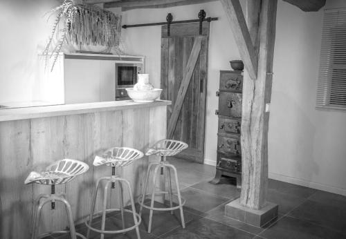 eine Küche mit drei Barhockern und einer Theke mit einem Schrank in der Unterkunft Bed en Box 3610 in Oirschot