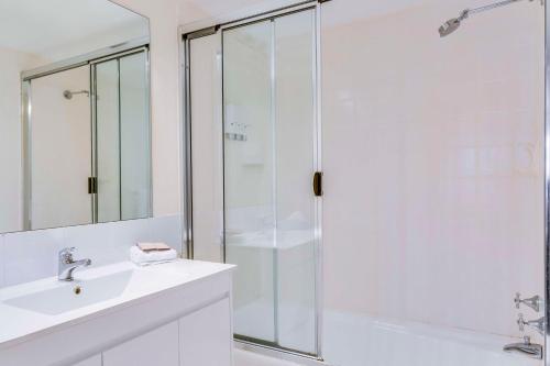 een witte badkamer met een douche en een wastafel bij Metro Apartments on King in Sydney
