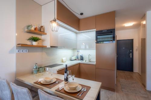 a kitchen with a wooden table with chairs and a dining room at LelleMarine by BLTN Apartmanok Balatonlelle in Balatonlelle