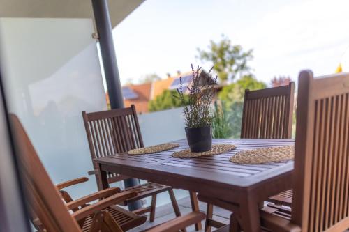 a wooden table with chairs and a potted plant on it at LelleMarine by BLTN Apartmanok Balatonlelle in Balatonlelle