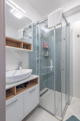 a bathroom with a glass shower and a sink at LelleMarine by BLTN Apartmanok Balatonlelle in Balatonlelle