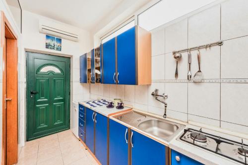 a kitchen with blue cabinets and a green door at Guest house Ivona in Split