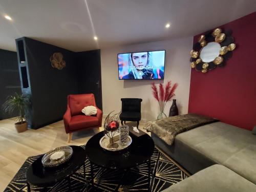 sala de estar con cama y TV en la pared en appartement cosy en Feigères