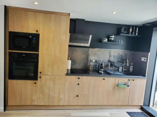 a kitchen with a large wooden cabinet with a microwave at appartement cosy in Feigères