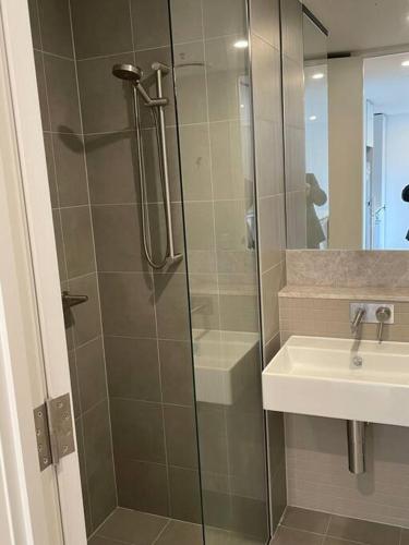 a shower with a glass door next to a sink at Lovely CBD two bedroom apartment free parking gym and sauna in Canberra