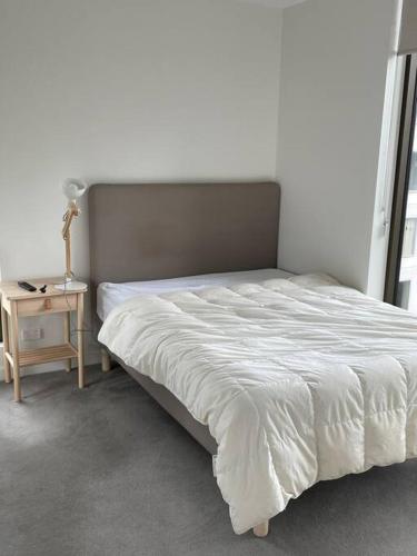 a bedroom with a bed and a night stand with a lamp at Lovely CBD two bedroom apartment free parking gym and sauna in Canberra