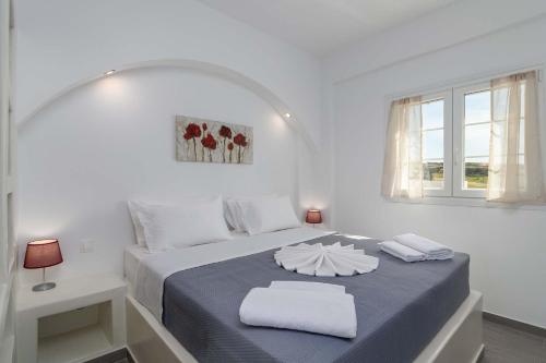a white bedroom with a bed with two towels on it at Sunset Village 1 in Paleochori