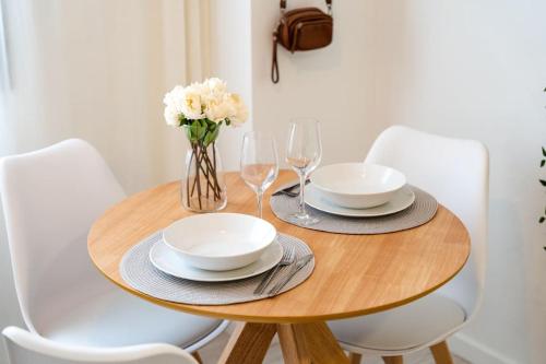a wooden table with plates and glasses and a vase of flowers at TwinSuites Malaga in Málaga