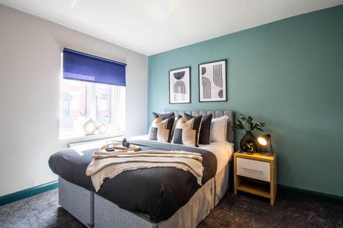 Cobden House - 5 Bed, 5 En-suite في Farnley: غرفة نوم بسرير كبير بجدران زرقاء