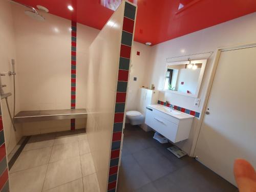 ein Bad mit einer rot-weißen gestreiften Wand in der Unterkunft La ferme du Riau in Aurouer