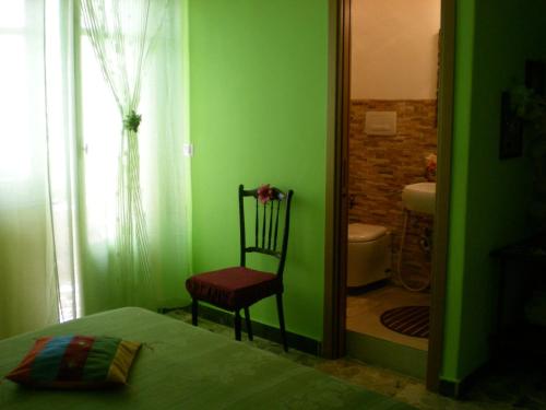 a green bedroom with a chair and a bathroom at Orizzonte B&B in Cefalù