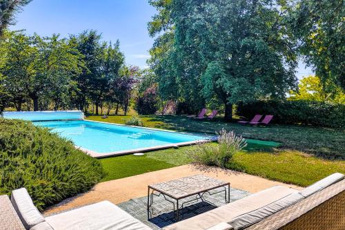 una piscina en un patio con sillas y mesa en L'Envolée Sauvage, en Cordes-sur-Ciel