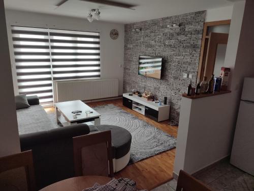 - un salon avec un canapé et un mur en briques dans l'établissement Apartman 2, à Foča