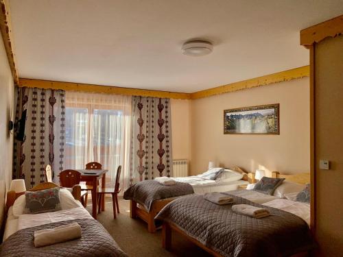 a hotel room with three beds and a table and chairs at Willa "NA KLINKU" in Dzianisz