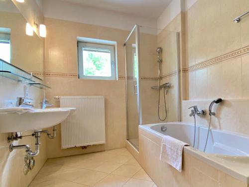 La salle de bains est pourvue d'une baignoire, d'un lavabo et d'une douche. dans l'établissement Villa Jasmin - Ferienwohnung 7, à Heringsdorf