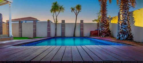 a swimming pool with a wooden deck and palm trees at B.R.O.Homes and Villas in Port Elizabeth