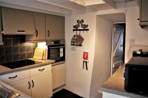 a kitchen with white cabinets and a counter top at The Roost - Askrigg 18th Century Cottage in Askrigg