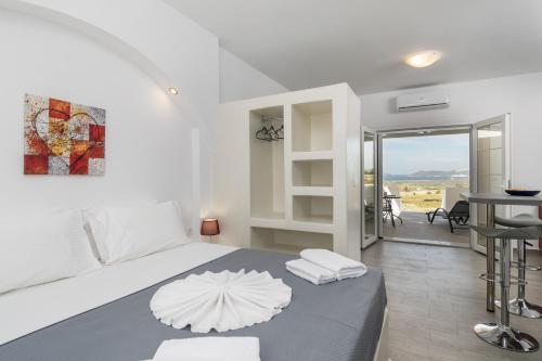 a white bedroom with a bed and a dining room at Sunset Village 2 in Paleochori