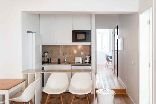 - une cuisine avec des placards blancs, une table et des chaises dans l'établissement Amaro - Elegant 2 bedroom apartment in Alcantara, à Lisbonne