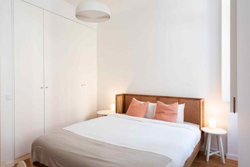 a bedroom with a bed with white sheets and pink pillows at Amaro - Elegant 2 bedroom apartment in Alcantara in Lisbon