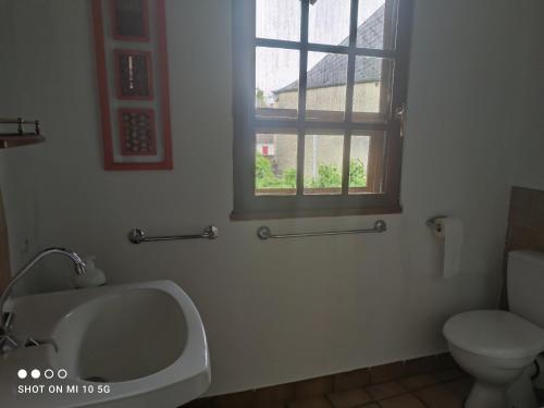 uma casa de banho com um lavatório, um WC e uma janela. em Les colombages bis em Pazayac
