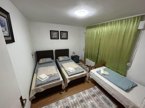 1 dormitorio con 2 camas y cortina verde en Apartman Reyan en Jajce